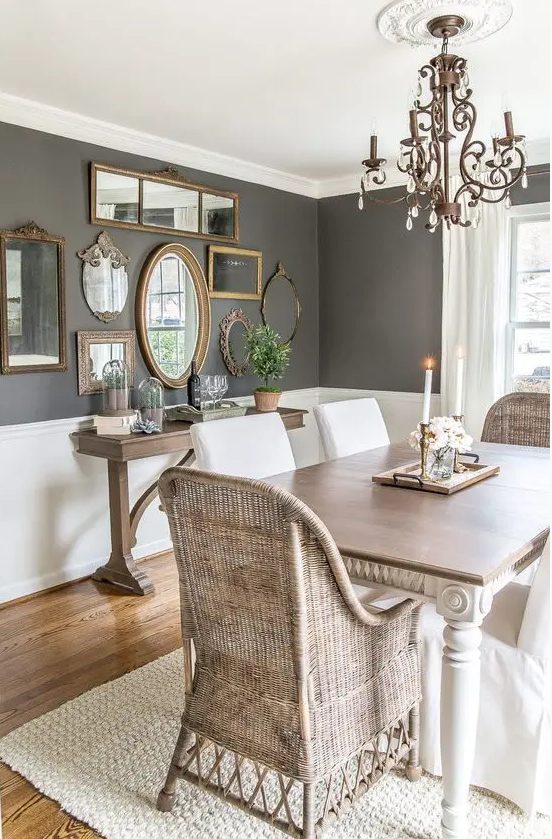 a stylish vintage dining room with slate grey walls with white wainscoting, a vintage dining table and woven chairs, a wooden console table