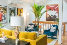 a vibrant mid-century modern space with a yellow sofa and blue chairs, floral pillows, potted plants and a credenza with a lamp