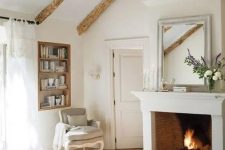 a vintage farmhouse bedroom in white and with wooden beams, with a fireplace, printed textiles