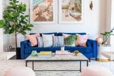 a vivacious living room with dark-stained beams, a bright sofa with colorful and printed pillows, blue poufs, a coffee table and cool prints