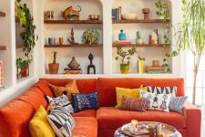 a vivacious living room with niches with built-in shelves, an orange sofa, bold textiles and potted plants for a maximalist feel