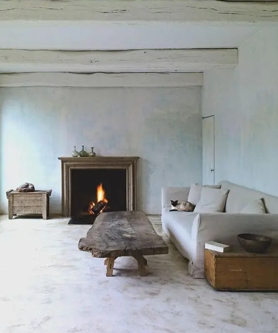 a wabi-sabi living room with neutral limewashed walls, a fireplace, a neutral sofa, a rough wood coffee table and chests
