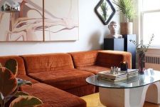 a whimsical space with a rust-colroed sectional, a quirky table, potted plants and a lovely artwork is wow