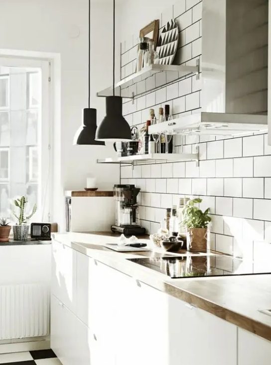 a white Scandinavian meets mid-century modern kitchen with sleke cabinets, butcher block, white subway tiles