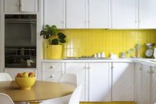 a white textural mid-century modern kitchen with a bright yellow backsplash, a matching lamp and pots, white chairs