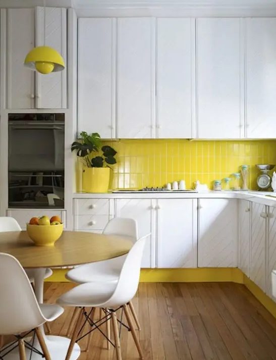 a white textural mid century modern kitchen with a bright yellow backsplash, a matching lamp and pots, white chairs