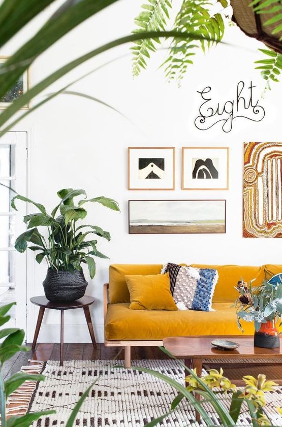 an airy and vivacious living room with a mustard sofa, a gallery wall, potted plants and a woven rug for a boho feel