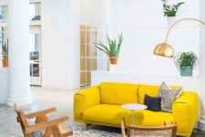 an airy living room with a neon yellow sofa, rattan chairs, a gold gallery wall and potted plants is amazing