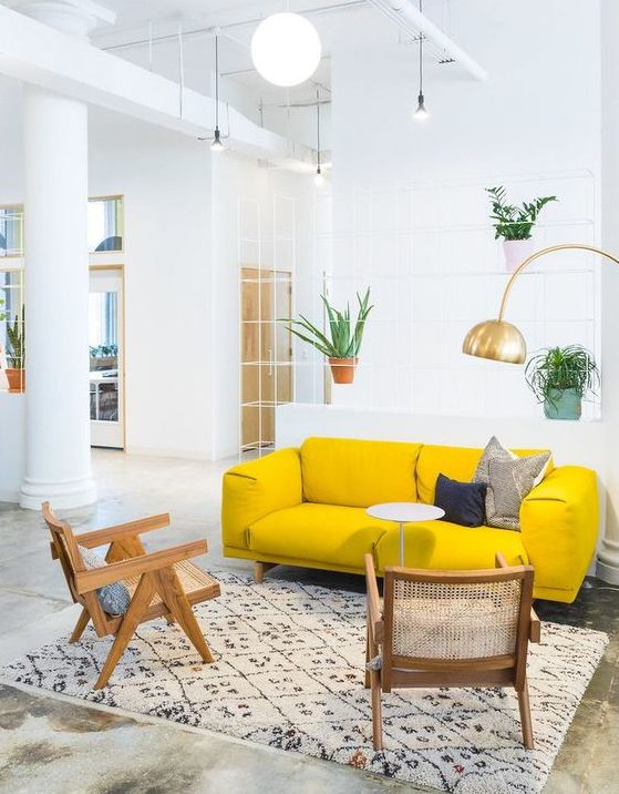 an airy living room with a neon yellow sofa, rattan chairs, a gold gallery wall and potted plants is amazing