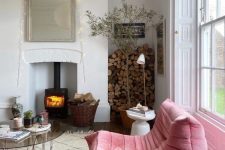 an eclectic living room with a hearth, pink loveseat, a glass table, firewood and side tables, potted trees and plants