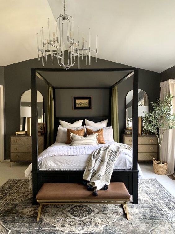 an elegant bedroom with grey walls, a black frame bed, chic dressers as nightstands and a leather bench at the foot of the bed