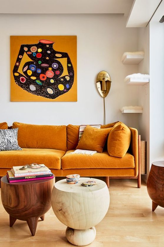 an exquisite living room with a honey yellow sofa, floating shelves for cats, round wooden tables and a bold artwork