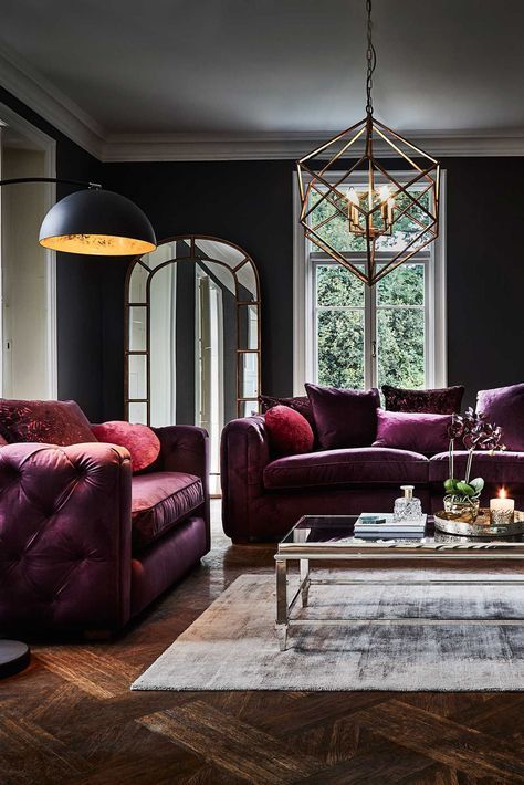 an exquisite living room with black walls, purple sofas, a glass coffee table, a pendant lamp and a black floor lamp plus orchids in a pot