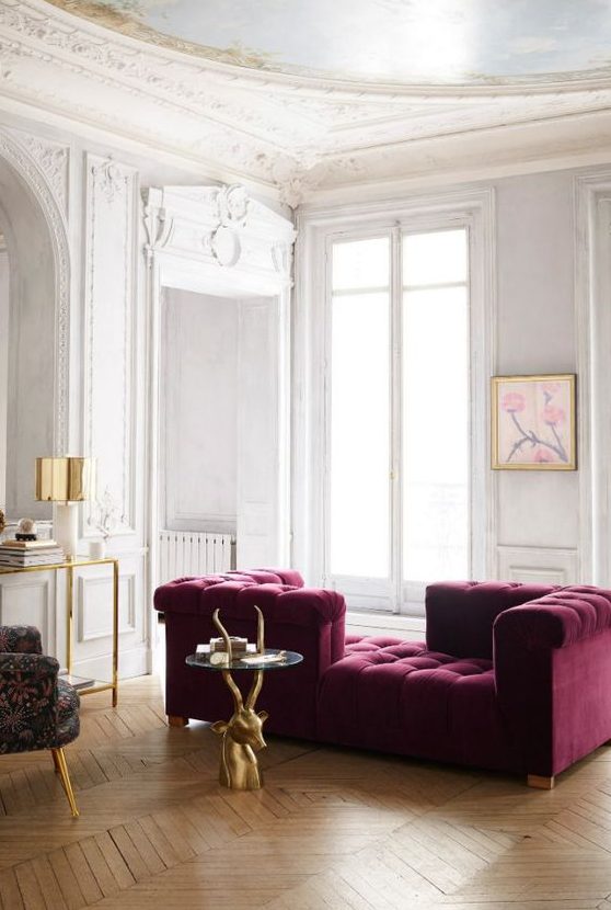 an exquisite neutral living room with a purple couch of velvet, a glass and gold console, a quirky chair and a cool antler table