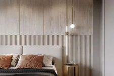 an inviting neutral contemporary bedroom with a planked accent wall, a neutral upohlstered bed, black and rust bedding, a pendant lamp and a leather bench