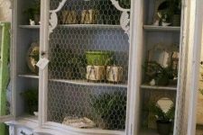 an oversized white shabby chic cupboard with chicken wire instead of glass that gives it a unique feel and a slightly rustic touch