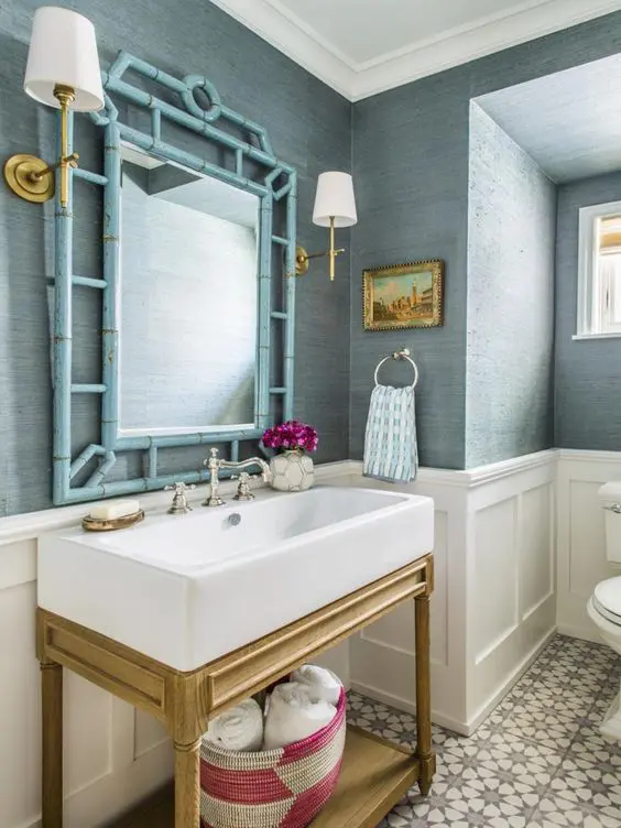 light blue grasscloth wallpaper goes nice with white paneling and gold touches, with a light-stained vanity