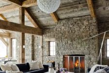 much stone, wooden beams and comfortable modern furniture upholstered with velvet and a cowhide rug
