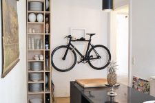 03 a chic contemporary dining and cooking space with an open storage shelf, a white rack for holding a bike, a black pendant lamp and a large kitchen island