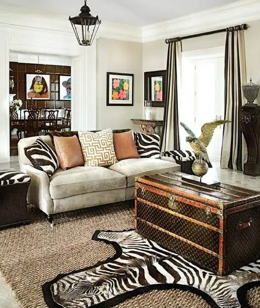 a bold living room with a grey sofa, zebra print pillows, a faux zebra rug, a dark chest for storage and some elegant black furniture pieces around