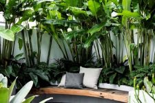 04 a minimalist tropical space with lots of plants and a single built-in bench with pillows and a deck – who needs more to enjoy the weather and the tropical feel