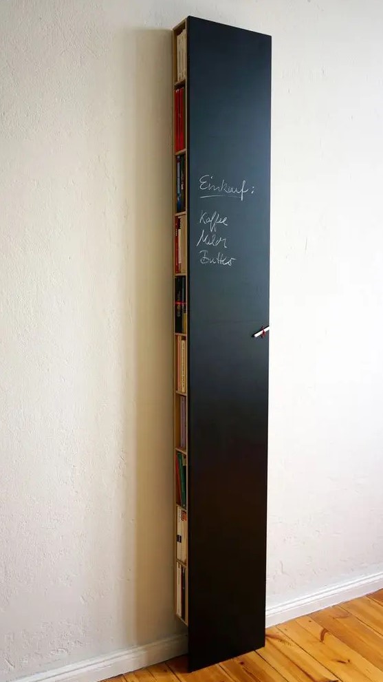 a tall and thin chalkboard storage unit hiding books, magazines and a wi fi router can double as a note board or an art one