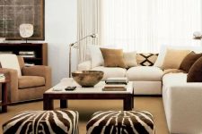 07 a modern living room with a creamy sectional with earthy pillows, a taupe chair, a large coffee table and zebra print poufs is cool