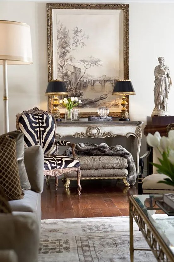 a sophisticated living room in neutrals, with a zebra print rug, vintage carved furniture pieces, black table lamps and cool art