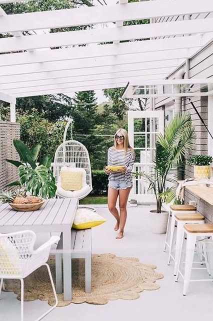 a tropical terrace with a pass through window as a bar counter and an eating space, potted plants and a rattan hanging chair for a tropical feel