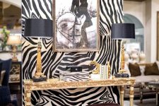 16 a very sophisticated nook accented with zebra print wallpaper, a beautiful inlay console table, burgundy leather stools, black and gold table lamps and an artwork