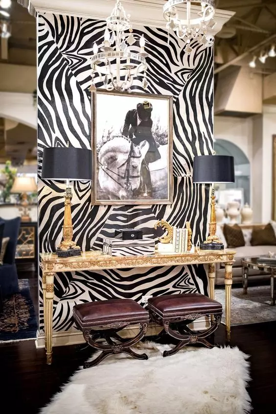 a very sophisticated nook accented with zebra print wallpaper, a beautiful inlay console table, burgundy leather stools, black and gold table lamps and an artwork