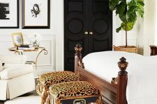 19 a gorgeous bedroom in neutrals, with black doors, a black and white gallery wall, a dark-stained bed with neutral bedding, a crystal chandelier and a couple of cheetah print stools