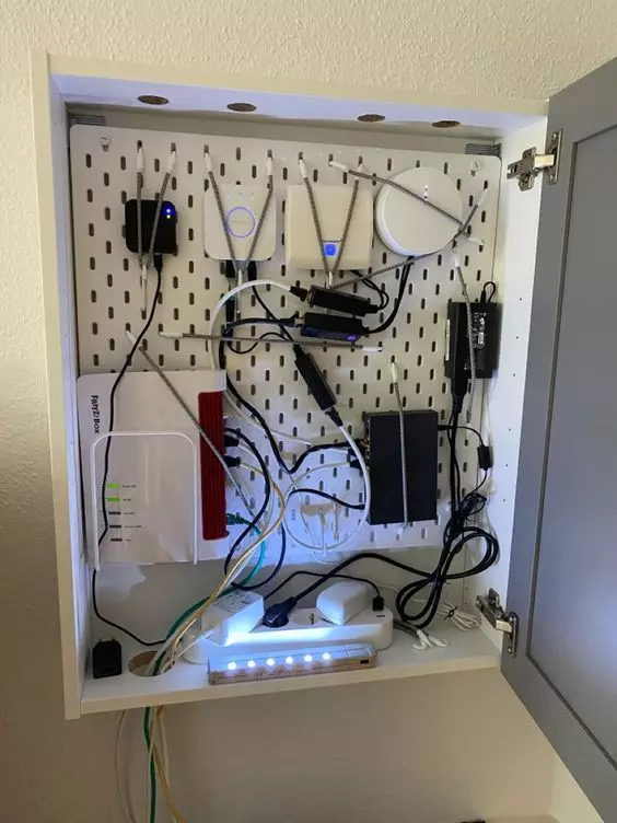 a wall mounted metal box with lots of cords and a wi fi router is a lovely idea to hide every eye sore