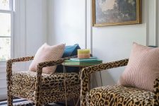 22 a stylish nook with a black and white striped rug, leopard print chairs, colorful pillows, a side table with books and a vintage artwork
