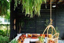 23 a beautiful tropical patio with a roof and greenery hanging down, with an L-shaped sofa with colorful pillows, a rattan chair and a mosaic tile floor
