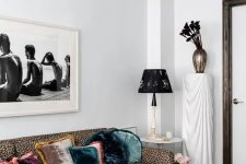 23 a whimsical living room with a leopard print sofa, a moody floral rug, a black coffee table, a print, a black chair and a vase with black callas