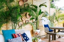27 a tropical boho patio with potted plants, a white sofa, boho rugs and an ottoman, a living edge table and decorative baskets on the wall