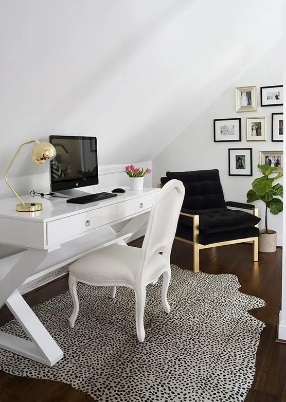 a chic and stylish attic work nook with a white desk and achair, a black chair, a stylish gallery wall, a Dolmatin print rug and touches of gold