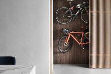 a hidden storage space with a pegboard wall and bikes attached to it and a sliding wood slab door allows hiding all your stuff