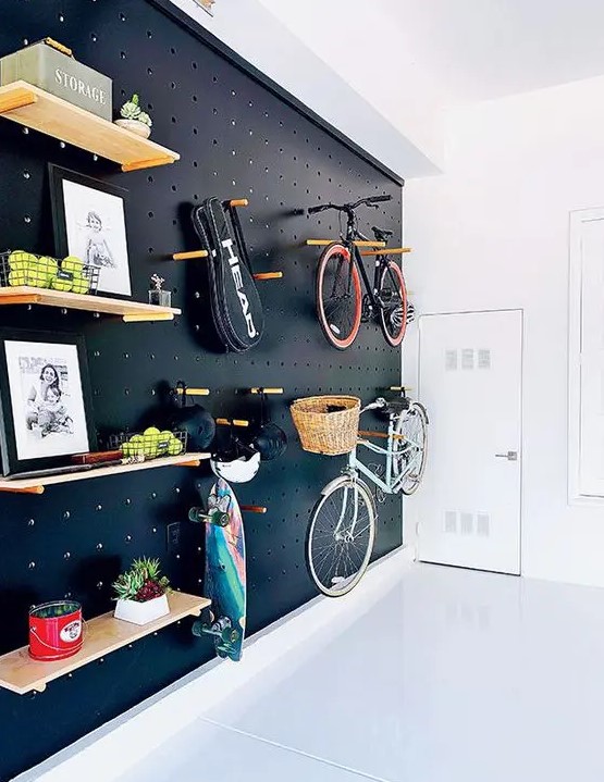 a light-filled entryway with a black pegboard wall with lots of shelves, hangers, hooks and with bike holders is a gorgeous idea for a contemporary space