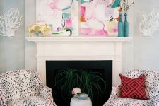 an airy pastel living room with a non-working fireplace, bold watercolor artwork, Dolmatin print chairs with pink edges and turquoise vases