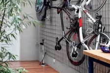 39 an outdoor space with a grid on the wall and bikes attached to the grid is a very cool and fresh idea to store them outdoors