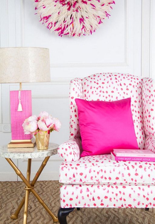 bright pink nook with a hot pink Dolmatin print chair and a pillow, a side table with a hot pink table lamp and a yarn decoration on the wall