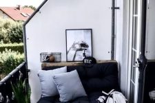 a Nordic balcony with a pallet loveseat with black upholstery, printed rugs and blankets, a black side table and a succulent