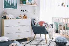 a Scandi nursery with bright touches – artworks, pillows, a pouf and a chair and some bright bedding in the crib is lovely