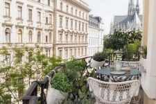 a Scandinavian balcony with a striped rug, white chairs and a black coffee table, potted greenery and fantastic views of Vienna
