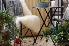 a Scandinavian balcony with black metal furniture, textural and printed textiles, crates and baskets and a red lantern is cool