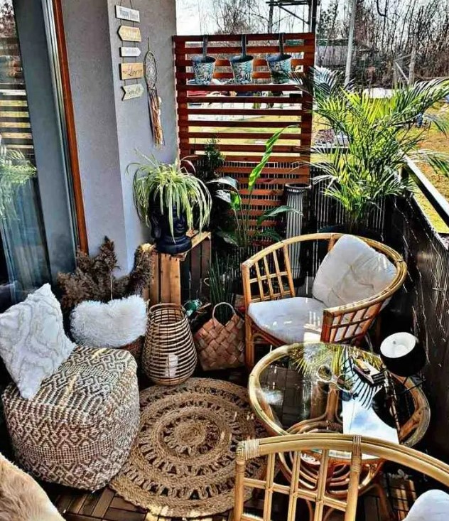 a boho balcony with rattan chairs and a table, a boho pouf and a pillow, a jute rug, potted greenery and candle lanterns is small but cool