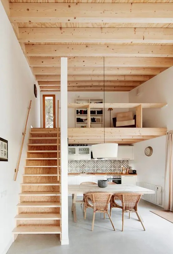 a contemporary home with a wooden ceiling and a staircase, with a kitchen down and a loft reading space with built-in shelves
