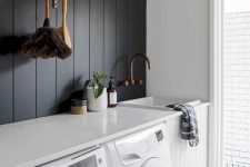 a contrasting laundry with a black shiplap wall, a white shiplap cabinet, white appliances and a countertop plus a door to the garden